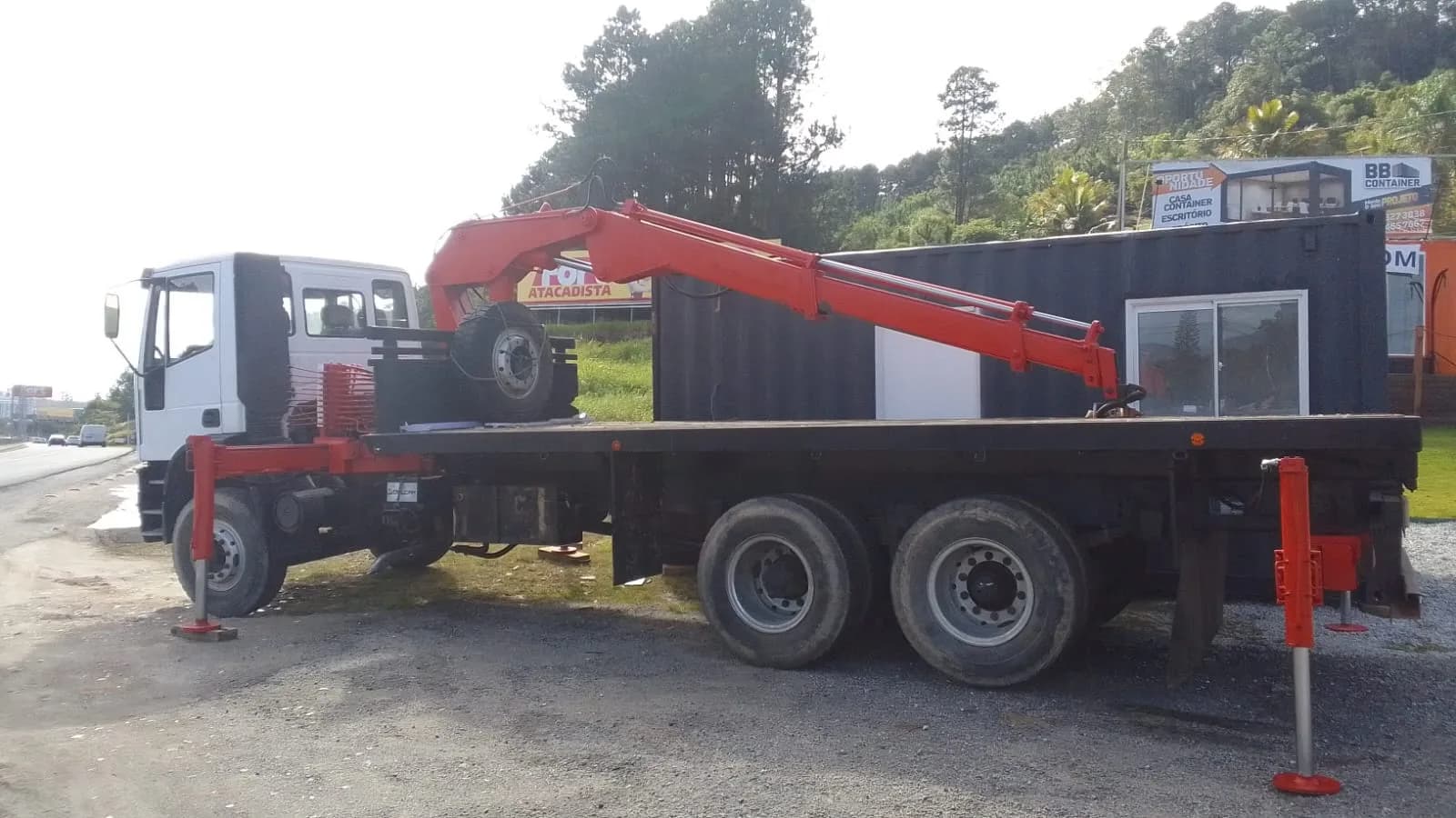 Caminhão Munck com braço do guindaste aberto e patolas apoiadas no chão